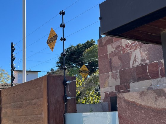 Cerco eléctrico de RC Sistemas sobre un portón de madera y un muro de mármol